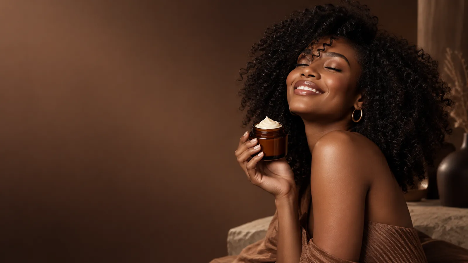 Smiling woman with natural curls holding a jar of hair butter